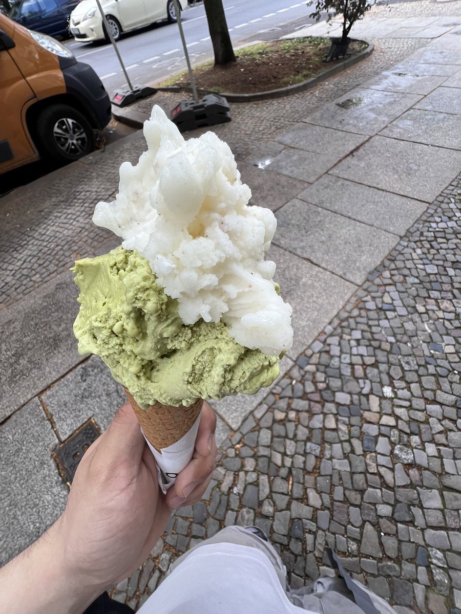 2 large scoops, on a waffle cone, one pistachio, the other vanilla
